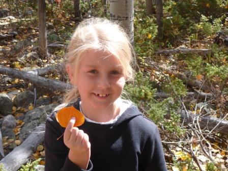 A young girl with a leaf she found while walking in the woods